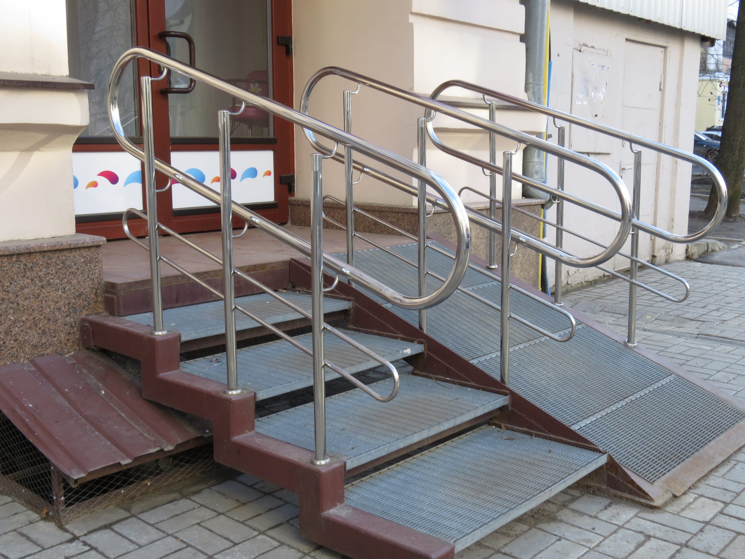 Two sets of stairs, one with a wheelchair ramp outside a building