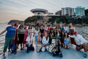 WEI's staff posing for a photo in a boat in front of a modern building.